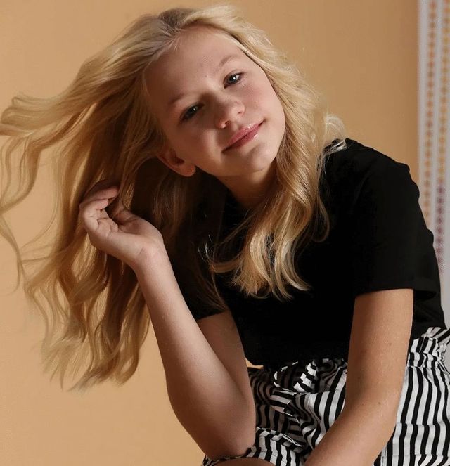 Volodymyr Zelenskyy' s daughter Aleksandra Zelenkaya posing in a black tops and a black striped white pants.
